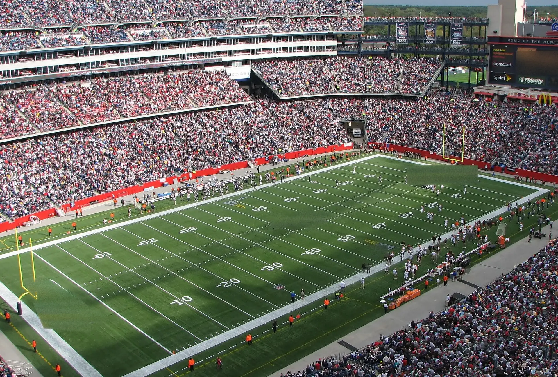 Gillette Stadium on a sunny game day, looking across the field from the upper deck toward the far stands and scoreboard tower